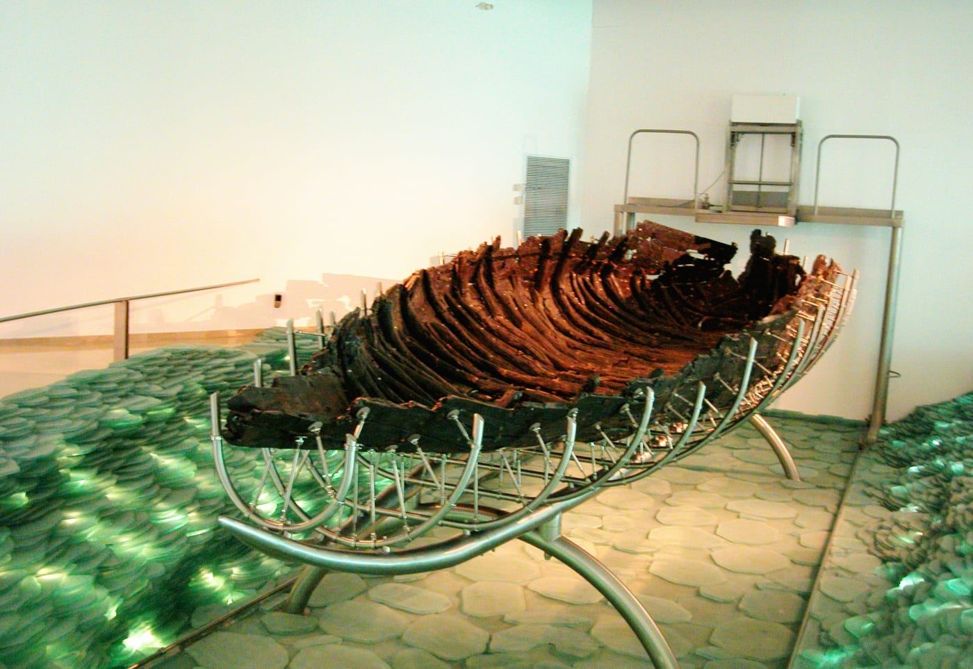 Barca de pesca del siglo I hallada en 1986 en el fango del mar de Galilea, junto a Ginosar, durante una sequía que dejó al descubierto la orilla; hoy conservada en el Museo Yigal Allon. La datación por radiocarbono y por la técnica de construcción la sitúa entre finales del siglo I a.C. y el siglo I d.C., es decir, es exactamente el tipo de barca que se usaba en el lago en tiempos de Jesús. No hay, sin embargo, ninguna prueba que la relacione con Jesús o con sus seguidores concretos: el apodo popular de 'barca de Jesús' es recepción devocional moderna, no un dato. Su valor real es documentar de forma directa la cultura material —la pesca en el lago— del entorno galileo en el que surgió el movimiento.
